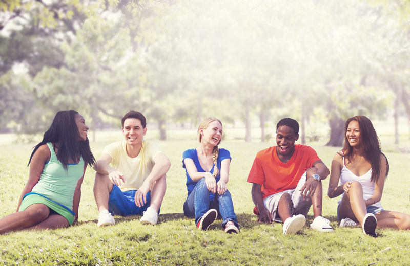 Teenagers sitting on the grass laughing